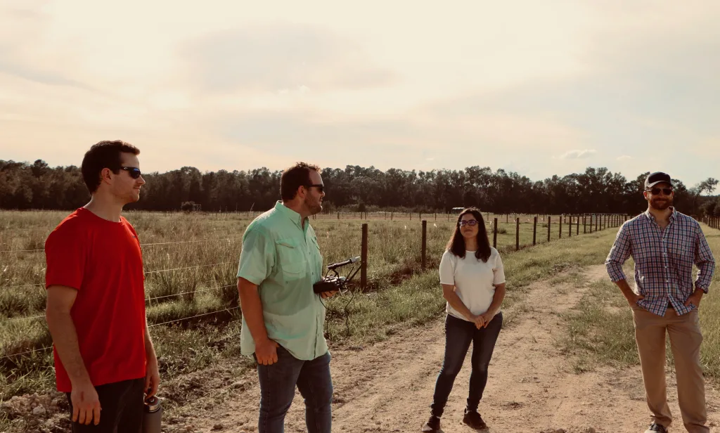 Hunter Smith, Dylan Stewart, Alina Zare and Chris Wilson standing near a cow pasture