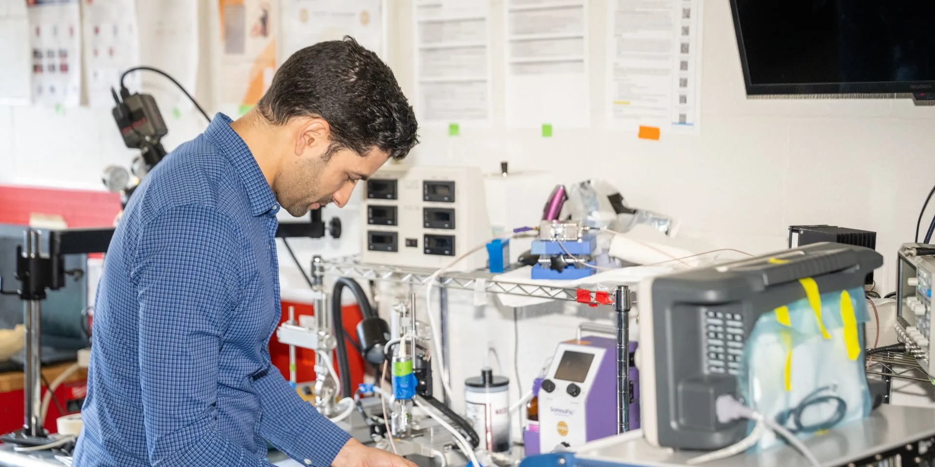 A man standing bent over at a work station in a lab
