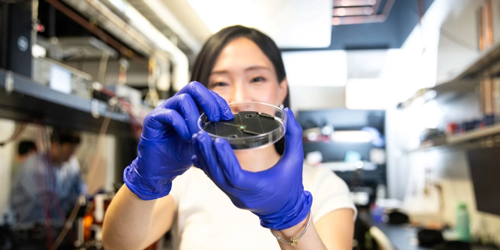 Laura Kim holds the quantum sensing platform — or diamond chip — her team developed in the lab.
